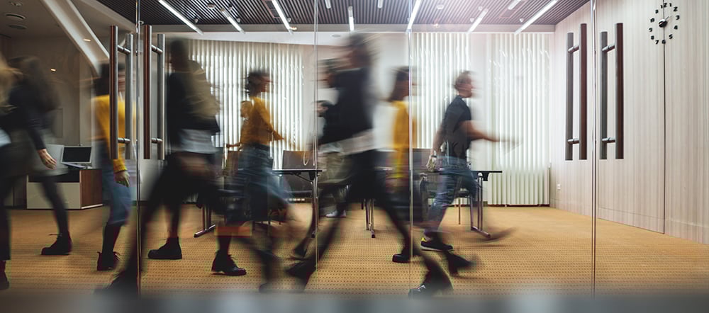 Workers walk in and out of a busy office foyer