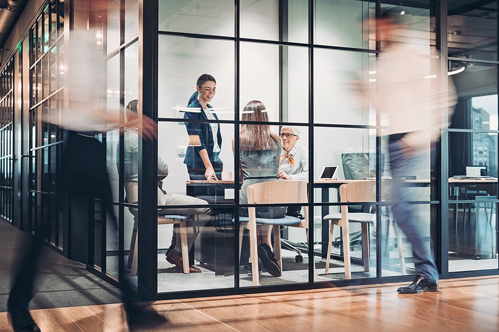Workers shuffle around busily in an office