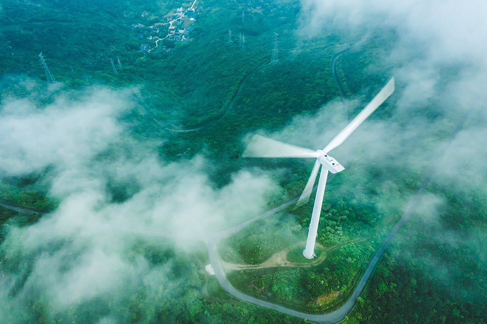 An aerial shot of a wind turbine on a hill